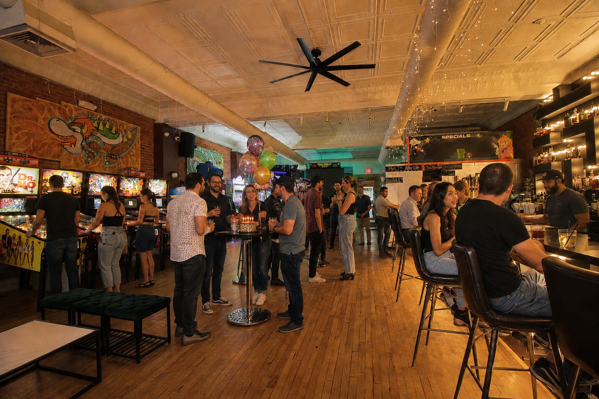 Guests mingling with drinks and balloons on the arcade floor at 1UP Arcade Bar
