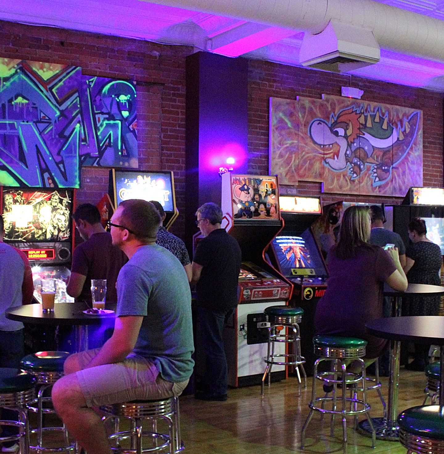 Neon-lit arcade floor at 1UP Arcade Bar in Downtown Farmington